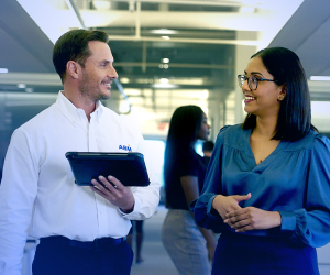 Male ABM employee holding a tablet and discussing services with female client 